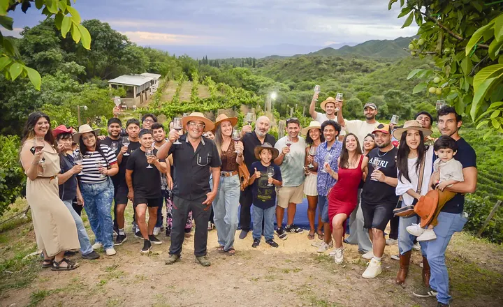 Grupo de visitantes brindando entre las viñas, con el cerro de fondo